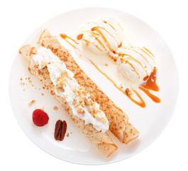 Serving pancakes with ice cream, nuts, raspberry and whipped cream on the plate. Decorated with caramel syrup. Isolated on white background. Top view.