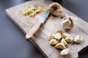 Garlic and knife on a wooden chopping board.
