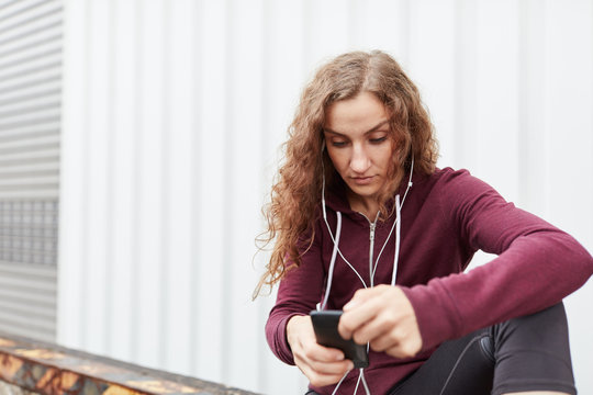 Sportliche Frau h&ouml;rt Musik &uuml;ber Smartphone App