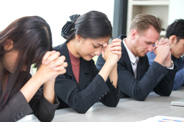 Business people pray together at meeting room. People in situation concept.