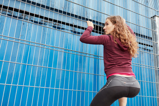 Sporty teenager training strength and coordination while climbing fence