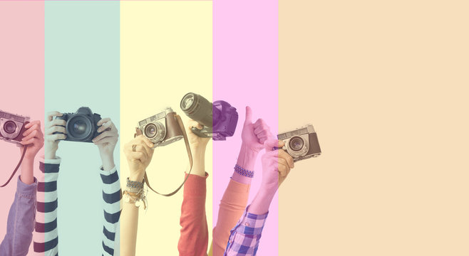Different color hands holding cameras in front of colorful background
