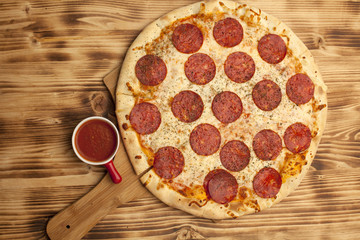 Pizza Peperone on wooden board served with ketchup