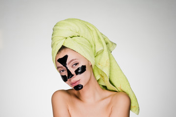 woman with a towel on her head apply a cleansing mask on her face