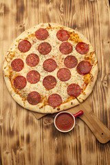 Pizza Peperone on wooden board served with ketchup