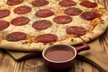 Pizza Peperone on wooden board served with ketchup