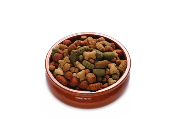 Dry colorful dog food in red porcelain bowl isolated on white background