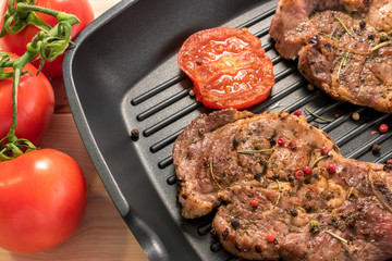Grilled steak on grill pan with tomatoes and spices close-up