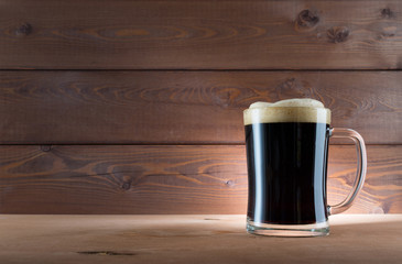 Glass of dark beer on wooden background