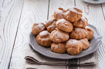 On the table there is a plate of profiteroles, a sweet dessert for breakfast