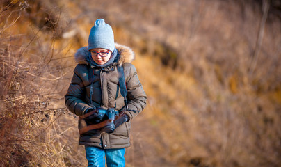 Boy with digital camera walking in the nature, hobby concept