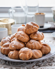 On the table there is a plate of profiteroles, a sweet dessert for breakfast