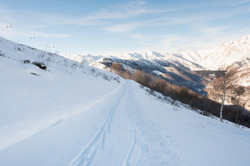 Fototapeta na wymiar Scenic mountain view on snowy off ski slope in sunny winter day at sunrise outdoor.