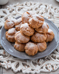 On the table there is a plate of profiteroles, a sweet dessert for breakfast