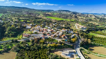 Aerial bird eye view of Goudi village in Polis Chrysochous valley, Paphos, Cyprus. View of traditional ceramic tile roof houses, church, trees, hills and Akamas - Latchi beach bay from above.