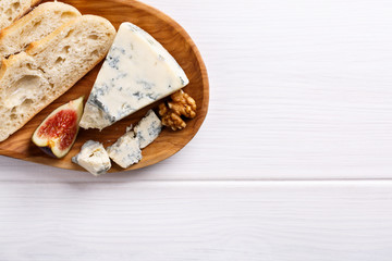 Cheese plate with blue cheese, grapes, figs, crackers and nuts on white table