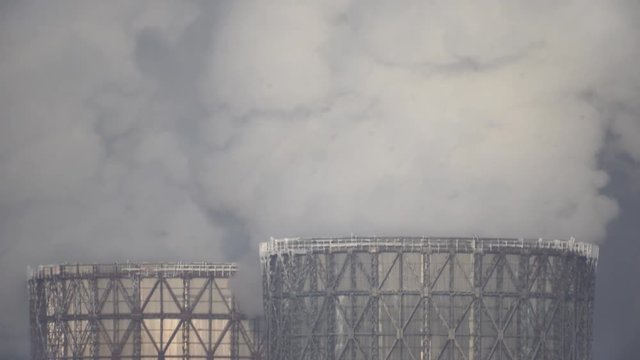 Cooling towers of a power plant. time lapse view of hyperboloid cooling towers emitting steam at the Electric Station in winter day. 4 k. Two smoking towers of power station