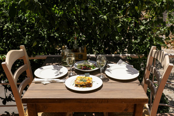 Traditional moussaka, village greek salad and white wine on the wooden table in greek tavern.