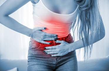 Young woman at home suffering from abdominal pain, close up