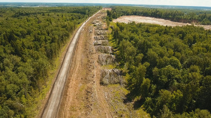 Construction of a new road in the forest area. Aerial view construction road place. Construction machinery for the construction of a road in the forest.