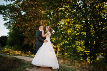 Newly married couple enjoying each other's company in the forest at sunset on their wedding day.