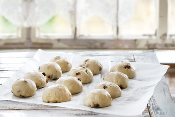 Raw unbaked buns. Ready to bake homemade Easter traditional hot cross buns on baking paper over...