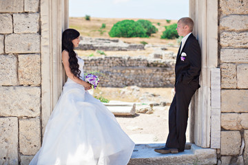 The bride and the groom leaned against the ancient wall. Wedding day.