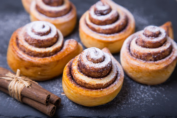 Fresh homemade buns with cinnamon, cinnamon sticks. Selective focus, close-up.