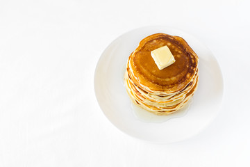 Stack of pancakes with butter and honey on white background