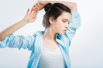 Little exercise. Brunette sweet pensive woman  rising hands while staying on the isolated background and staring aside