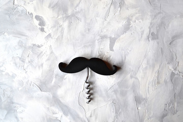 One corkscrew with black handle in the form of a mustache on textured background.