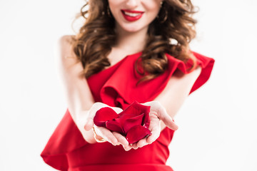 cropped image of smiling attractive girl showing red rose petals in hands isolated on white