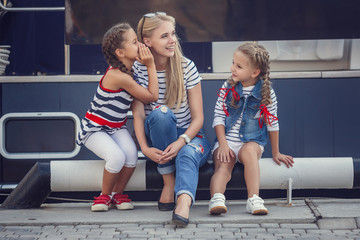Obraz premium The elder sister and younger sisters and a brother in a marine style against the backdrop of boats and yachts. Idea and concept Friendship, vacation, vacation, family