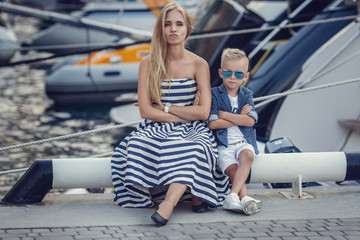 The elder sister and younger sisters and a brother in a marine style against the backdrop of boats and yachts. Idea and concept Friendship, vacation, vacation, family