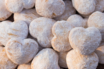 Fototapeta na wymiar Background of heart shaped cookies covered with powdered sugar