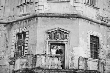 Beautiful wedding couple posing next to the main castle doors. Black and white photo.