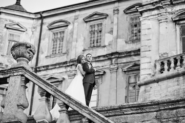 Obraz na płótnie Canvas Fabulous wedding couple walking around the castle territory on their festive day. Black and white photo.