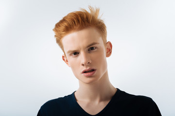 Fototapeta premium Sunny future. Nice mediative pretty guy standing on the isolated background and looking in far while thinking 