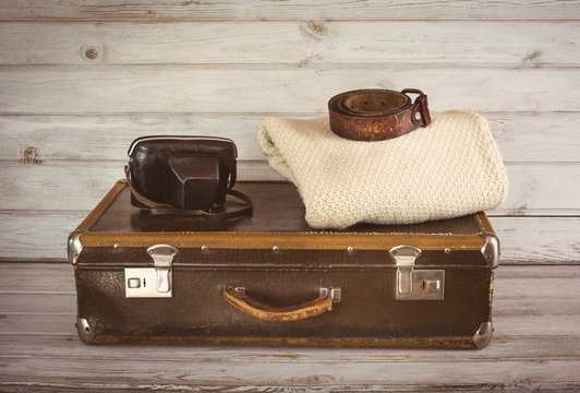 Old vintage suitcase in the room on wooden light board.