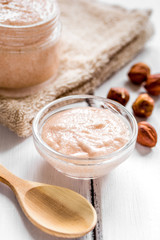 cosmetic set with hazelnut scrub on table background