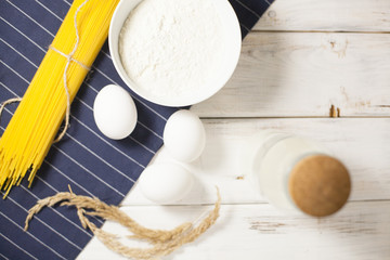 Cooking Homemade Spaghetti with eggs, flour, milk on a blue tablecloth, white wooden background, selective focus, top view
