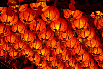 A lot of lighted Chinese paper lanterns hanging from the ceiling of a Taoist temple in Taiwan.
