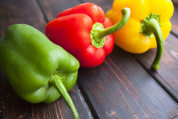 Diet, Healthy Food Cooking, Vegetarian Concept. Green, red and yellow sweet paprika peppers on a rustic wooden background , close up