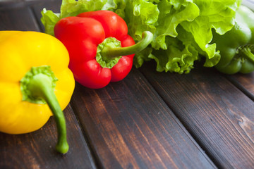 Diet, Healthy Food Cooking, Vegetarian Concept. Lettuce leaves, red and yellow sweet paprika peppers on a rustic wooden background with copy space