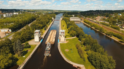 Fototapeta na wymiar Sluice Gates on the River. Aerial view barge, ship in the river gateway. River sluice construction, water river gateway. Shipping channel.