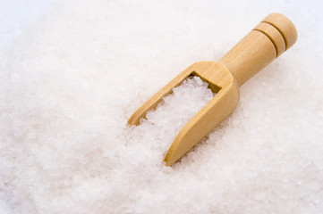 Wooden scoop on sea salt background