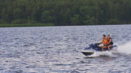 People riding on a jet ski. High speed jetski with water spray. People rid on water scooter.