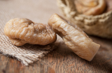 figues séchées tombant d'un petit panier en osier sur fond en bois et toile de jutte