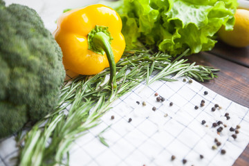 Diet, Healthy Food Cooking, Vegetarian Concept. Vegetables, herbs and spices: broccoli, lettuce, lemon, rosemary, sea salt and black pepper, dark wood and napkin as a background