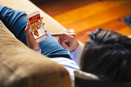 Pizza shopping app in a mobile phone screen. Woman holding the smart phone in the hand.
